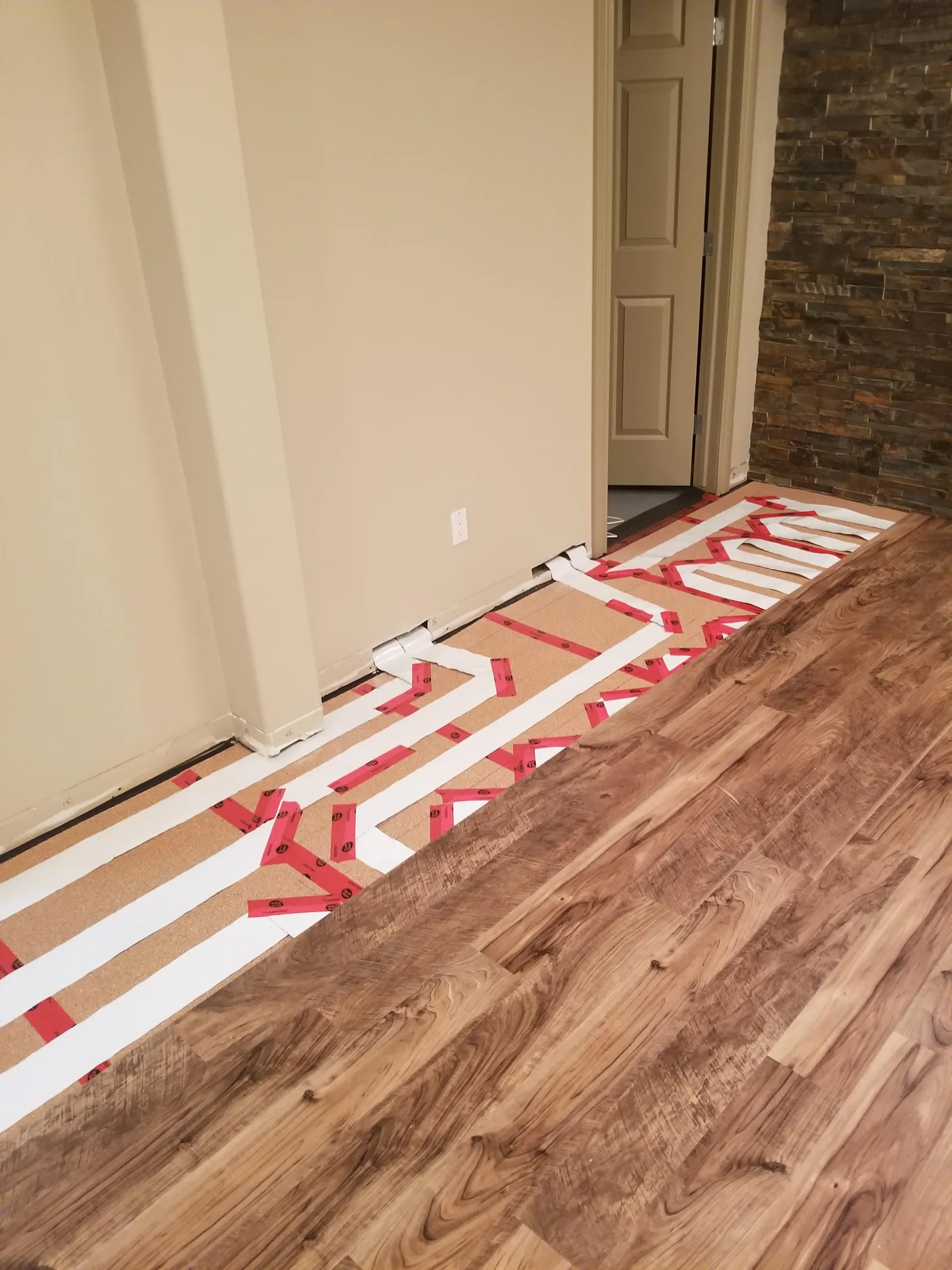 Instalación real de DomoFLEX: la cinta radiante desapareciendo bajo el piso de madera a medio colocar