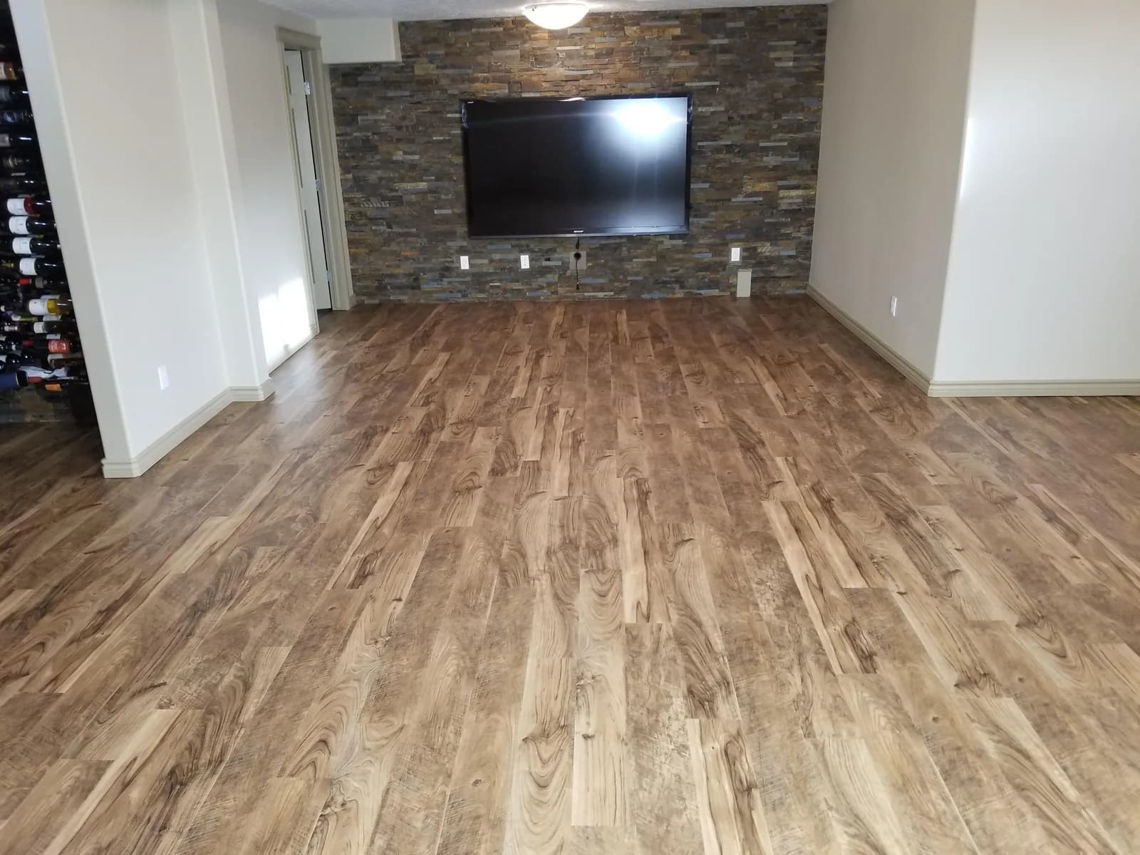 Sala terminada con piso de madera y muro de piedra, con DomoFLEX instalado bajo el piso